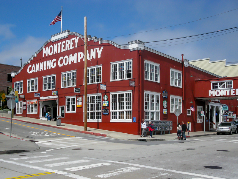 Image of large red wooden building with large white letters saying Monterey Canning Company