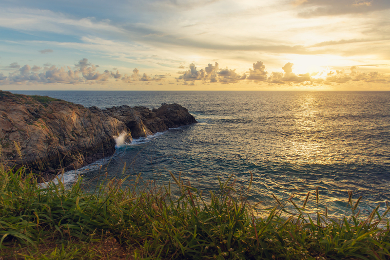 Image of rocky outcrop jutting into the sea under golden sunset